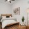 A large bed in a room with a lamp, a window, and a plant