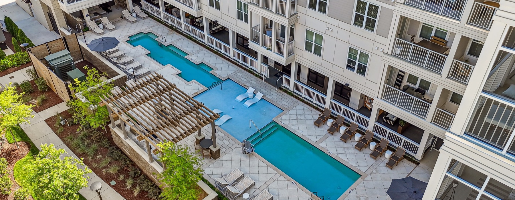  A large apartment complex with a pool and a patio area.