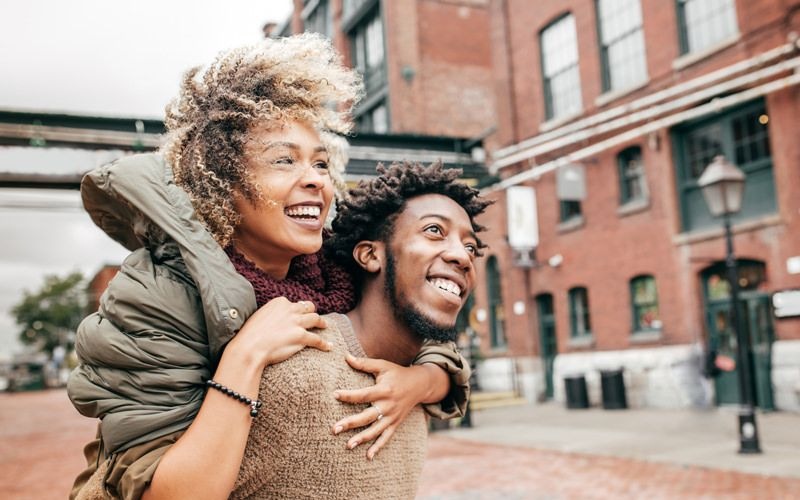 Man and woman walking along a neighborhood street and smiling.